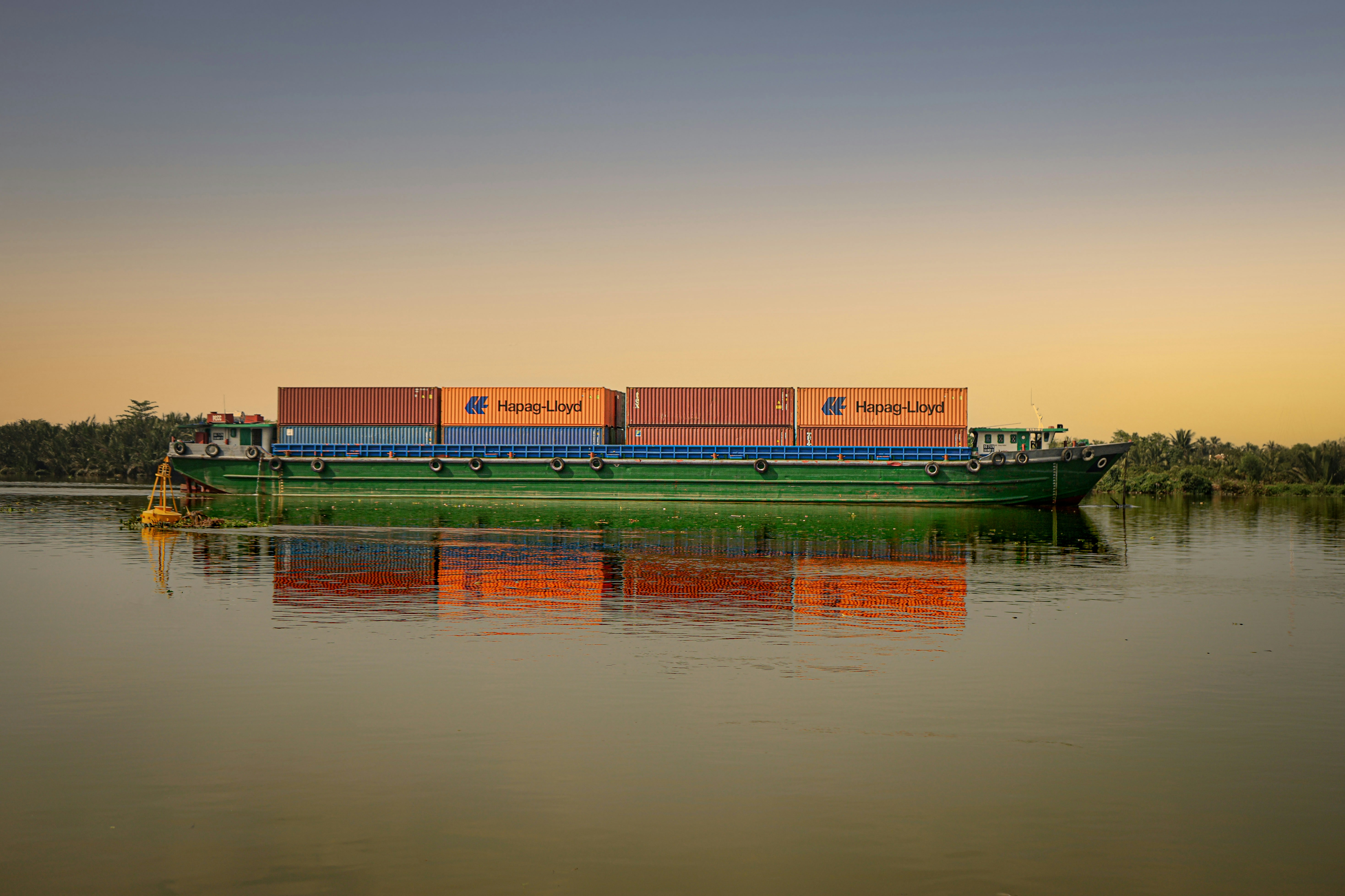 Container verdi e arancioni sullo specchio d'acqua durante il giorno