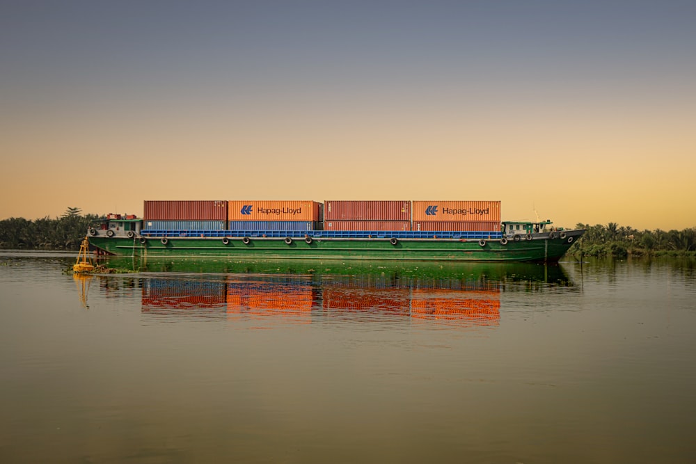 green and orange cargo containers on body of water during daytime