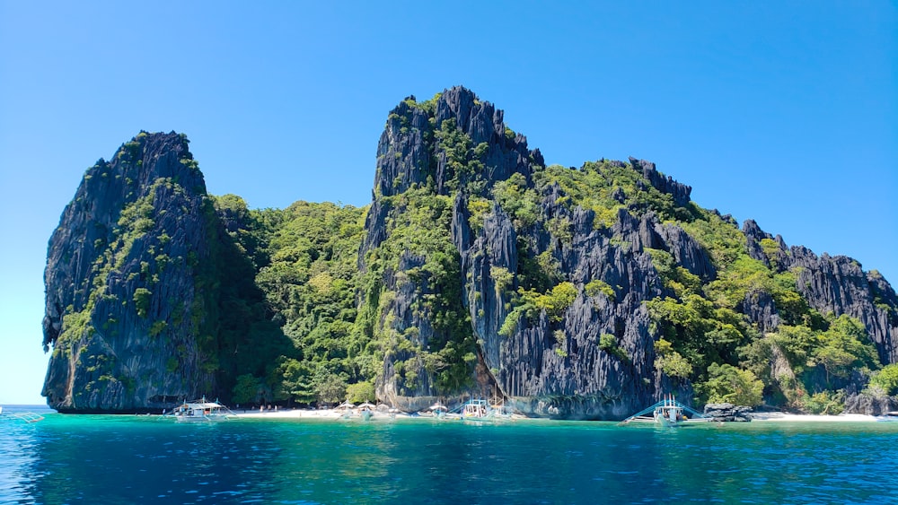 green and gray rock formation beside blue sea under blue sky during daytime