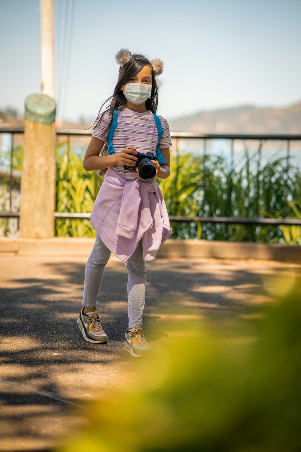 woman in white t-shirt and white pants holding black camera