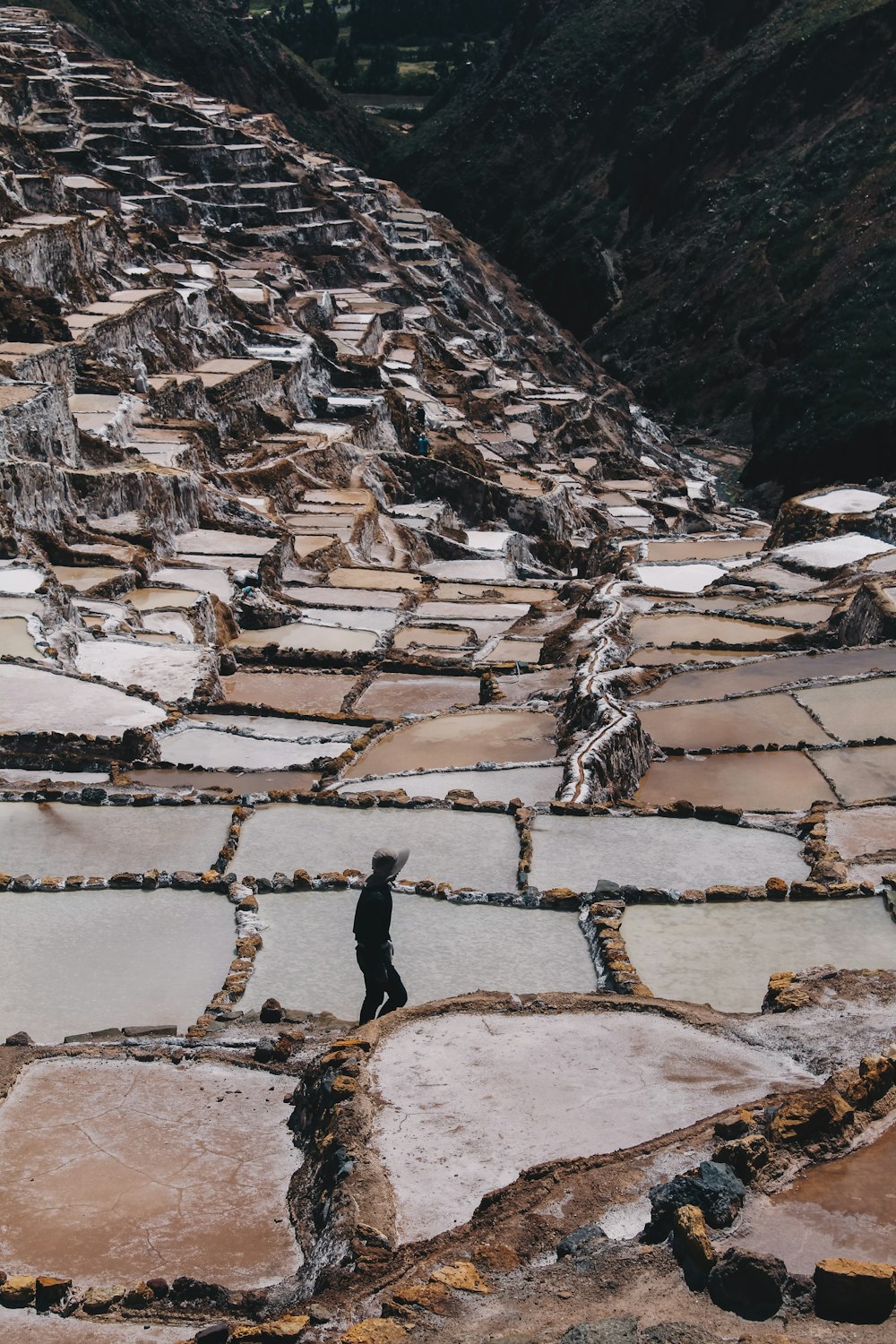 Persona in piedi sulla formazione rocciosa marrone durante il giorno