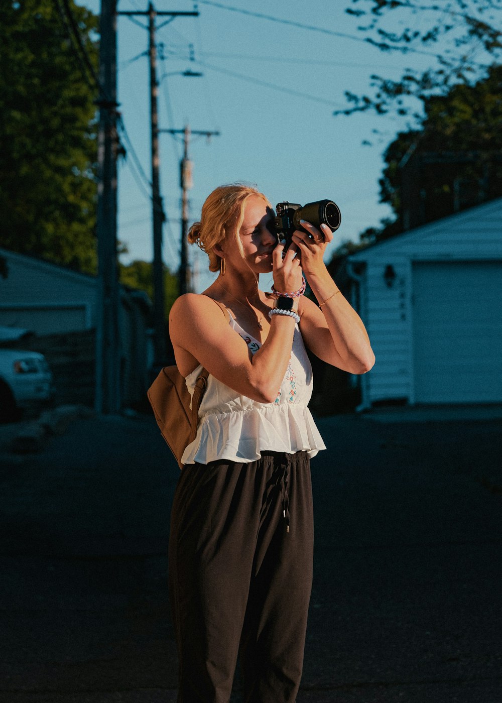 Mujer con vestido blanco sin mangas sosteniendo una cámara DSLR negra