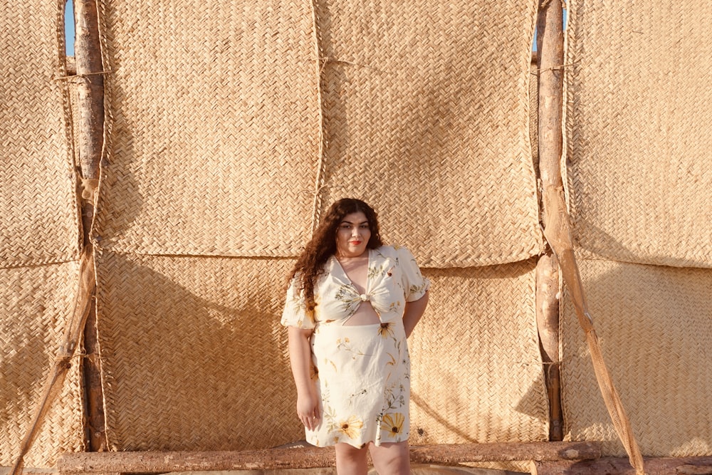 donna in abito bianco che si appoggia al muro marrone