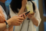 woman in white shirt holding black smartphone