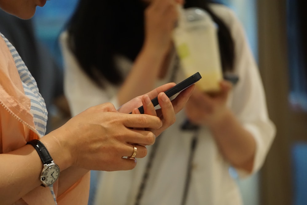 woman in white shirt holding black smartphone