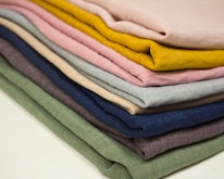 Close-up of folded surgical uniforms in various vibrant colors neatly stacked on a shelf.