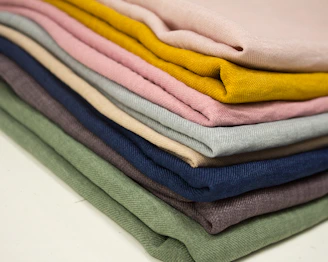 Stacks of neatly folded quilting fabrics in different textures and prints.