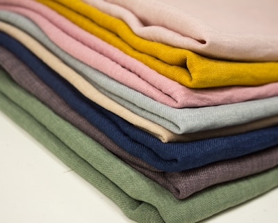 Close-up of folded surgical uniforms in various vibrant colors neatly stacked on a shelf.