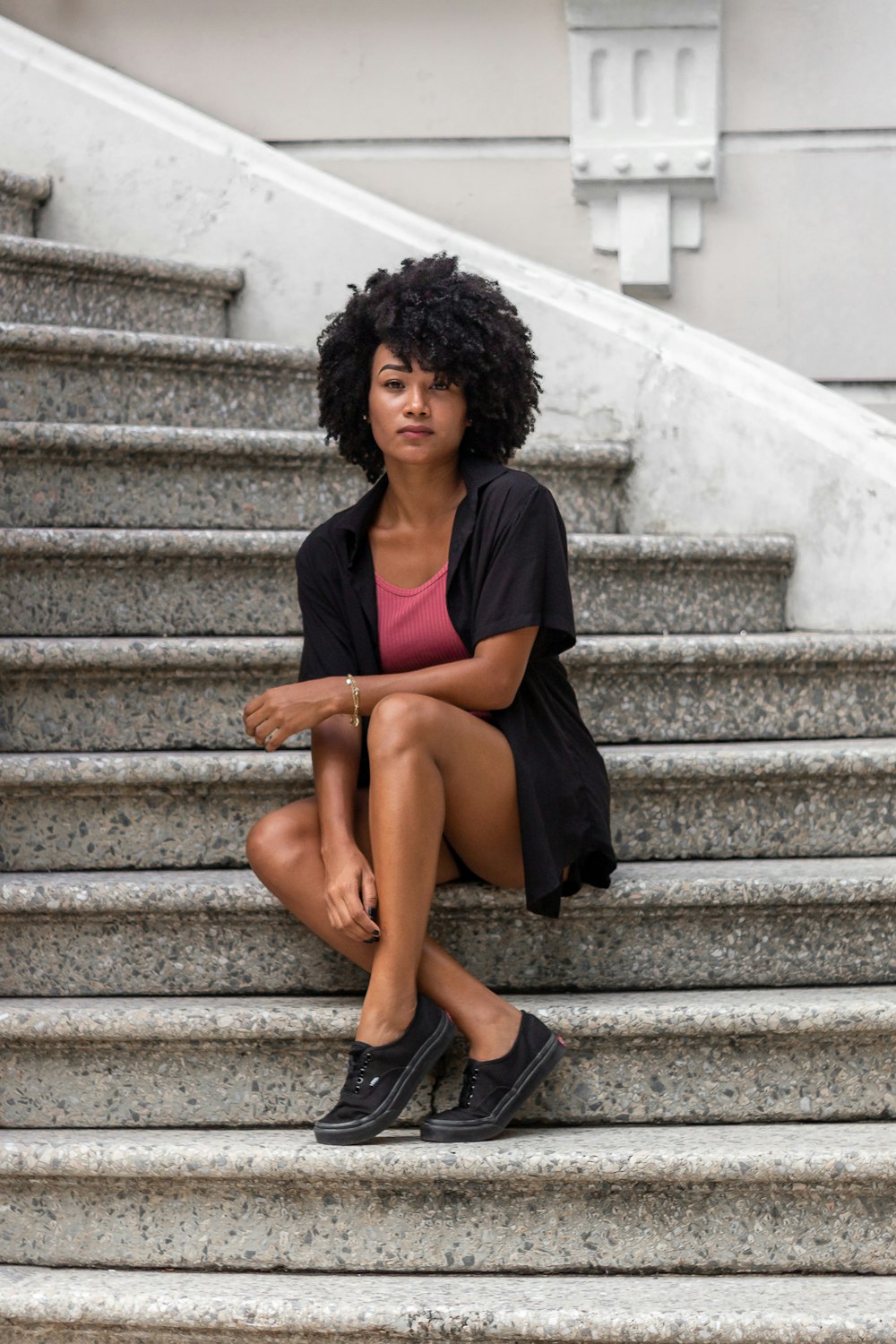 woman in black dress sitting on gray concrete stairs