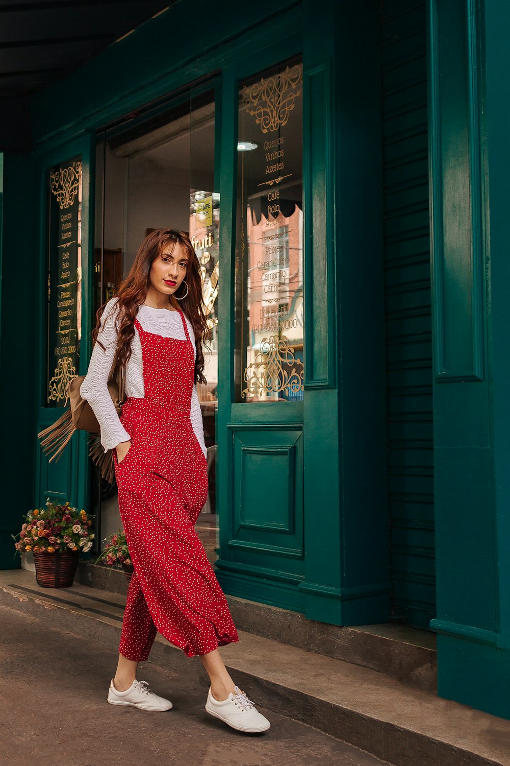 woman in red and white dress standing beside blue wooden door during daytime