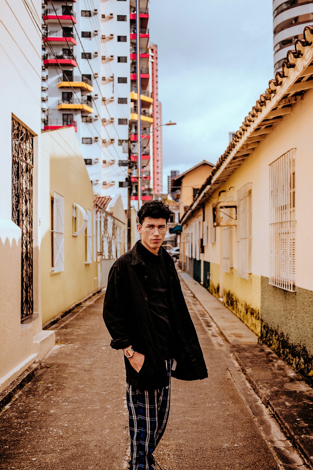 man in black coat standing on sidewalk during daytime