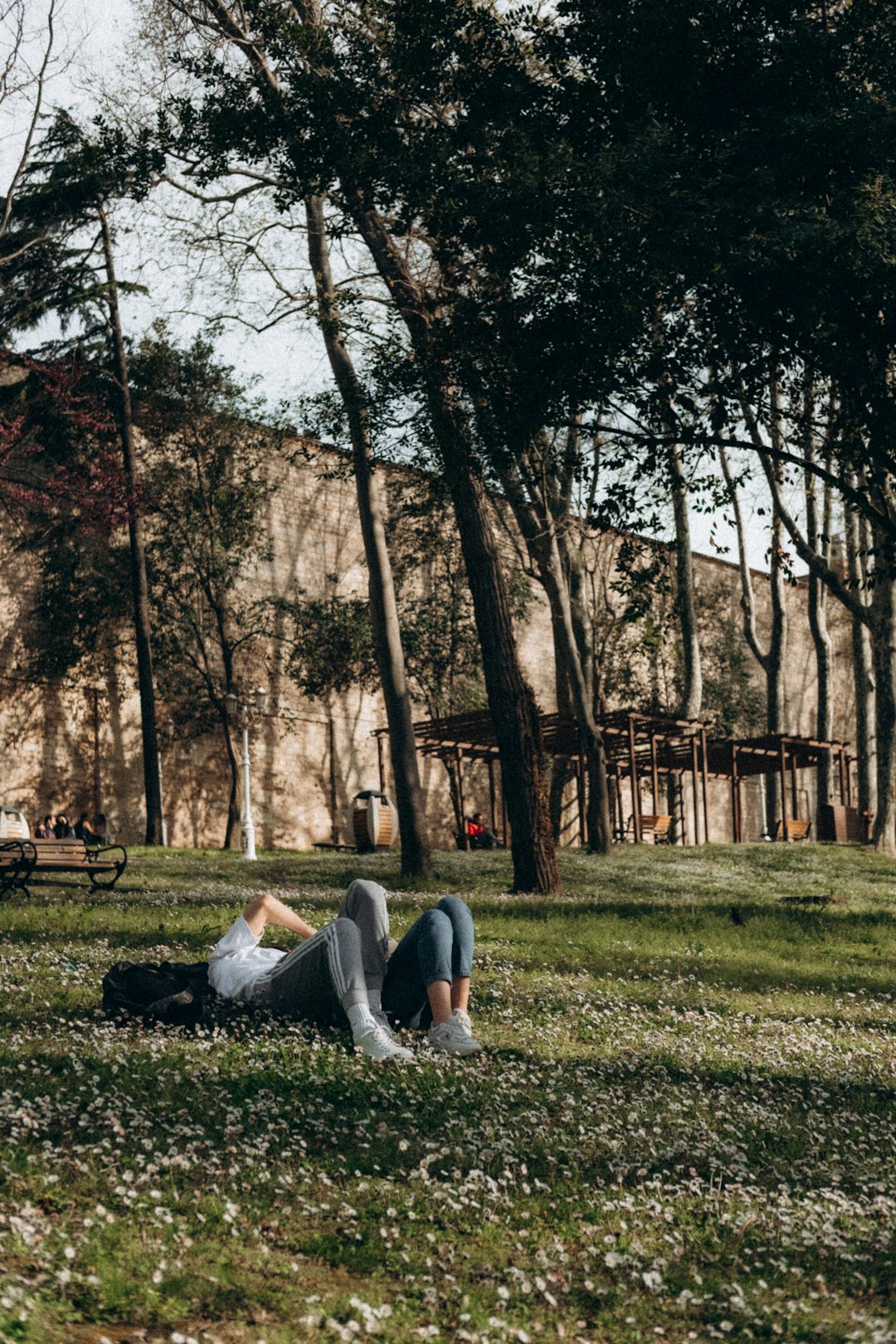 woman in white shirt and white pants sitting on grass field