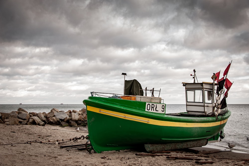 green and white boat on shore during daytime