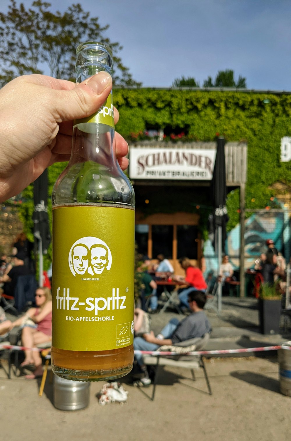 Eine Person, die eine Flasche Sprudel hält - Spotz vor einer Menschenmenge