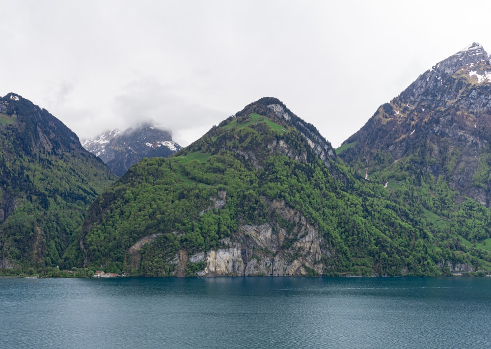 Montagne verte à côté d’un plan d’eau pendant la journée