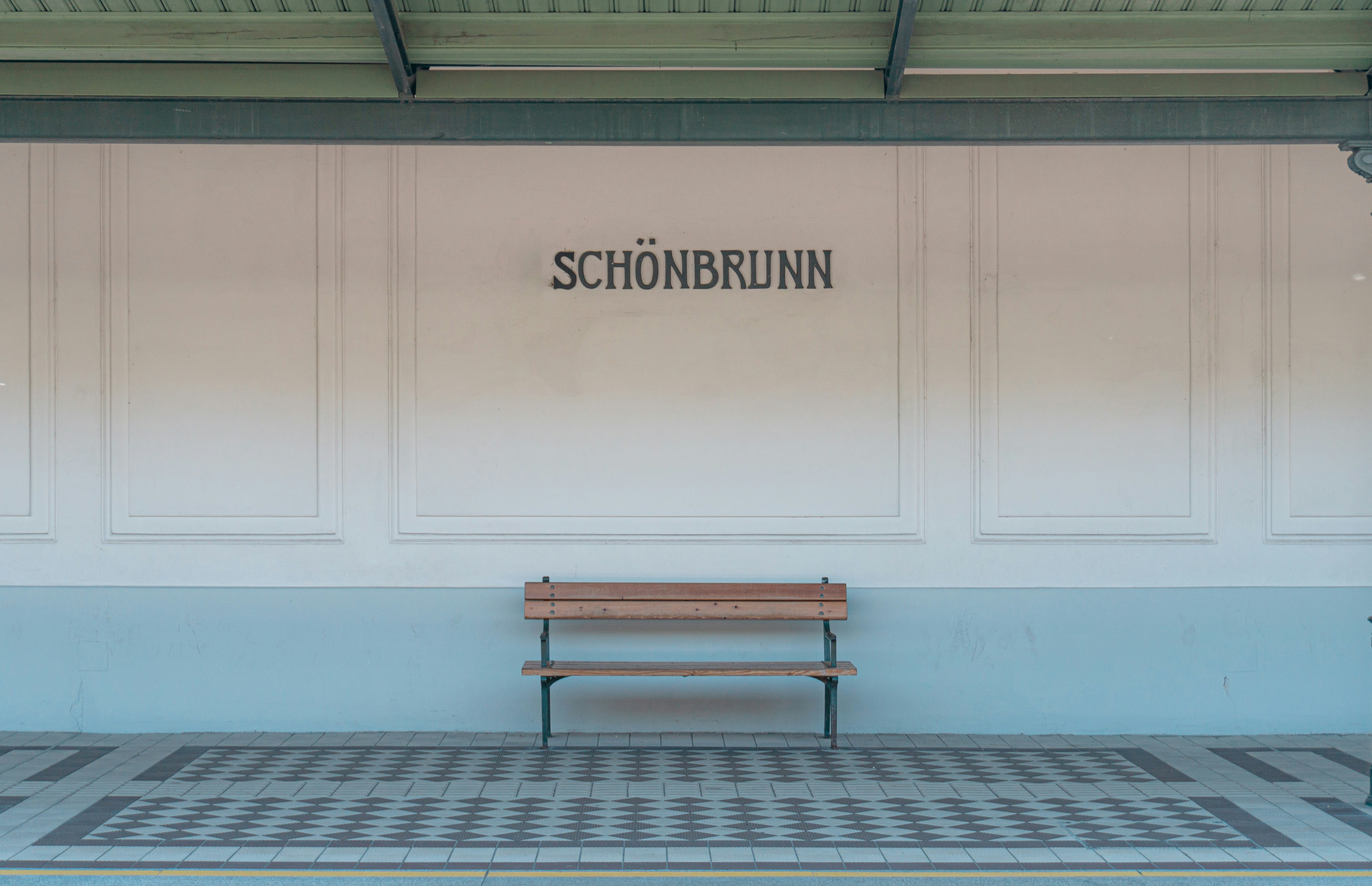 brown wooden bench near white wall