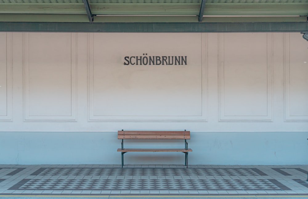 brown wooden bench near white wall