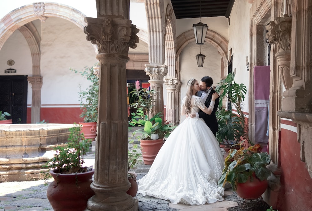 Frau im weißen Hochzeitskleid in der Nähe von braunem Betonpfosten