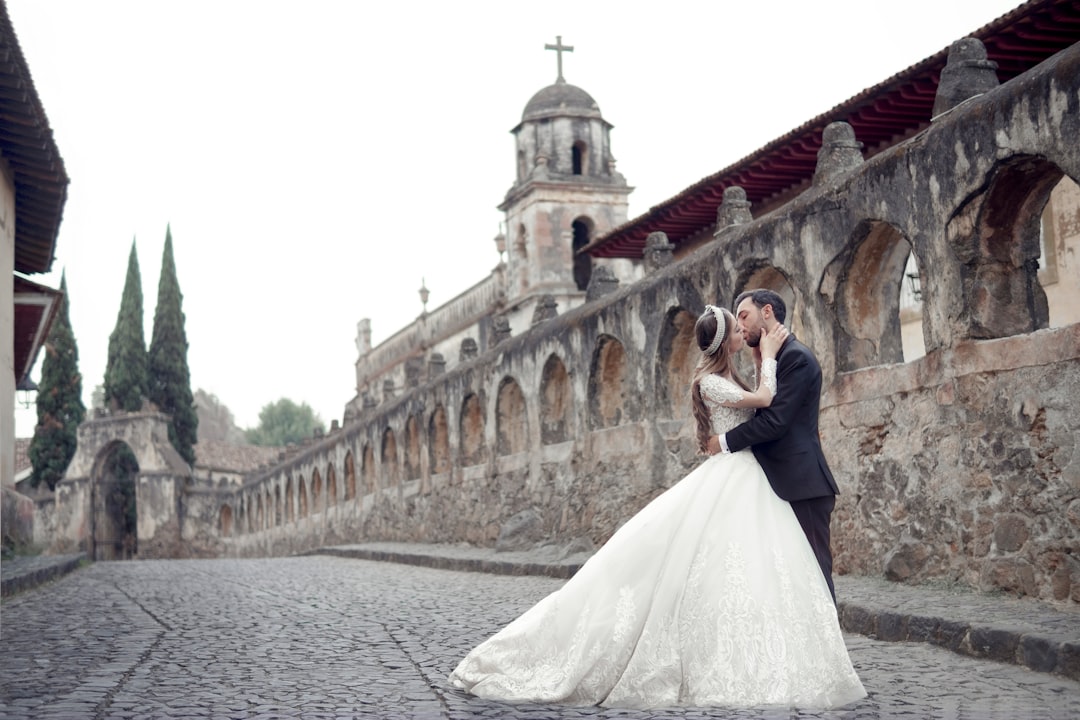 bride and groom standing on gray concrete bridge during daytime