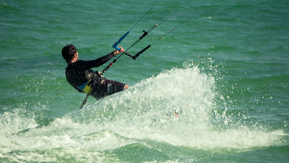 man in black wet suit riding on white surfboard during daytime