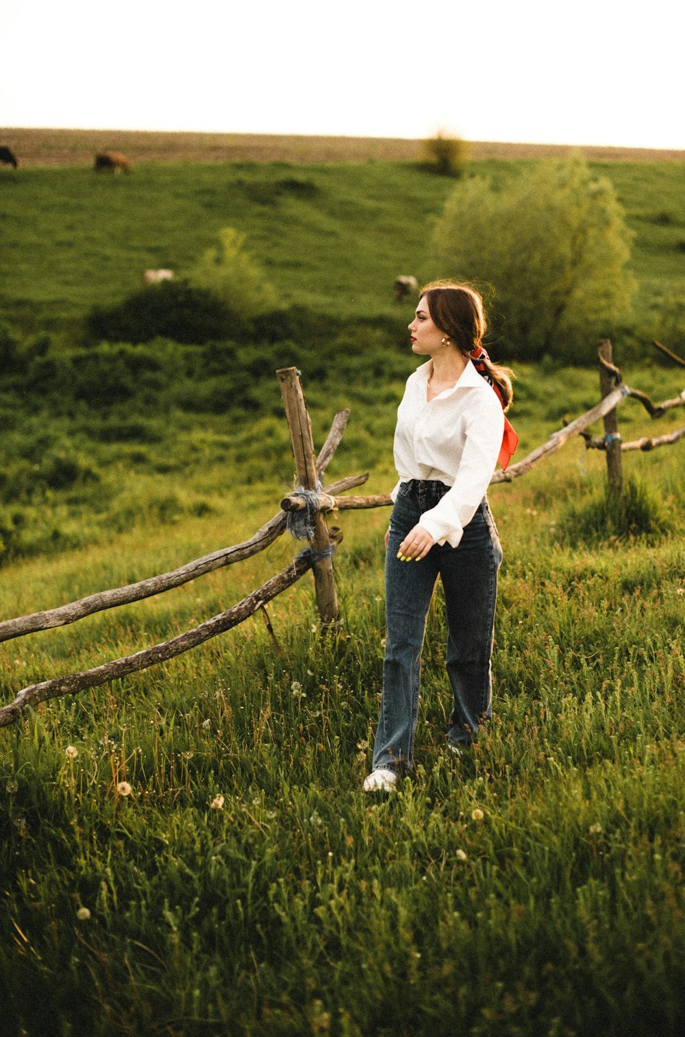 woman in white long sleeve shirt and blue denim jeans standing on green grass field during