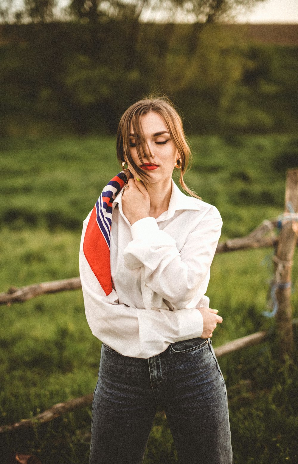 woman in white long sleeve shirt and blue denim jeans standing on green grass field during