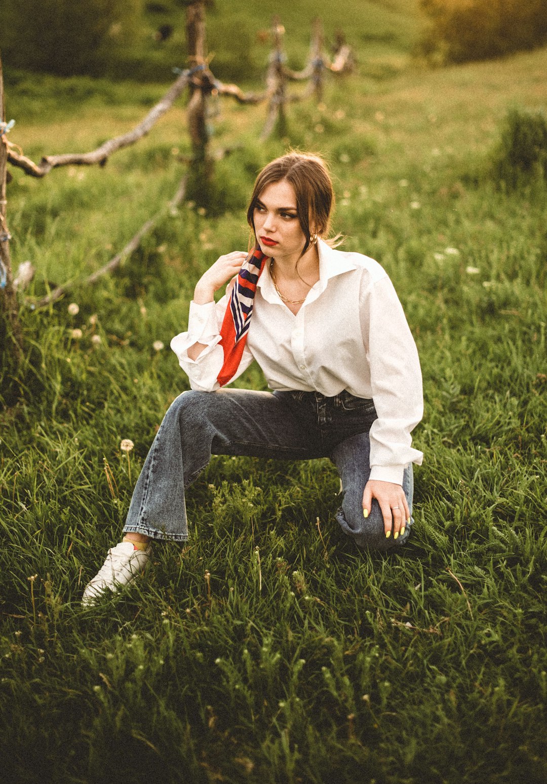 woman in white long sleeve shirt and blue denim jeans sitting on green grass field during