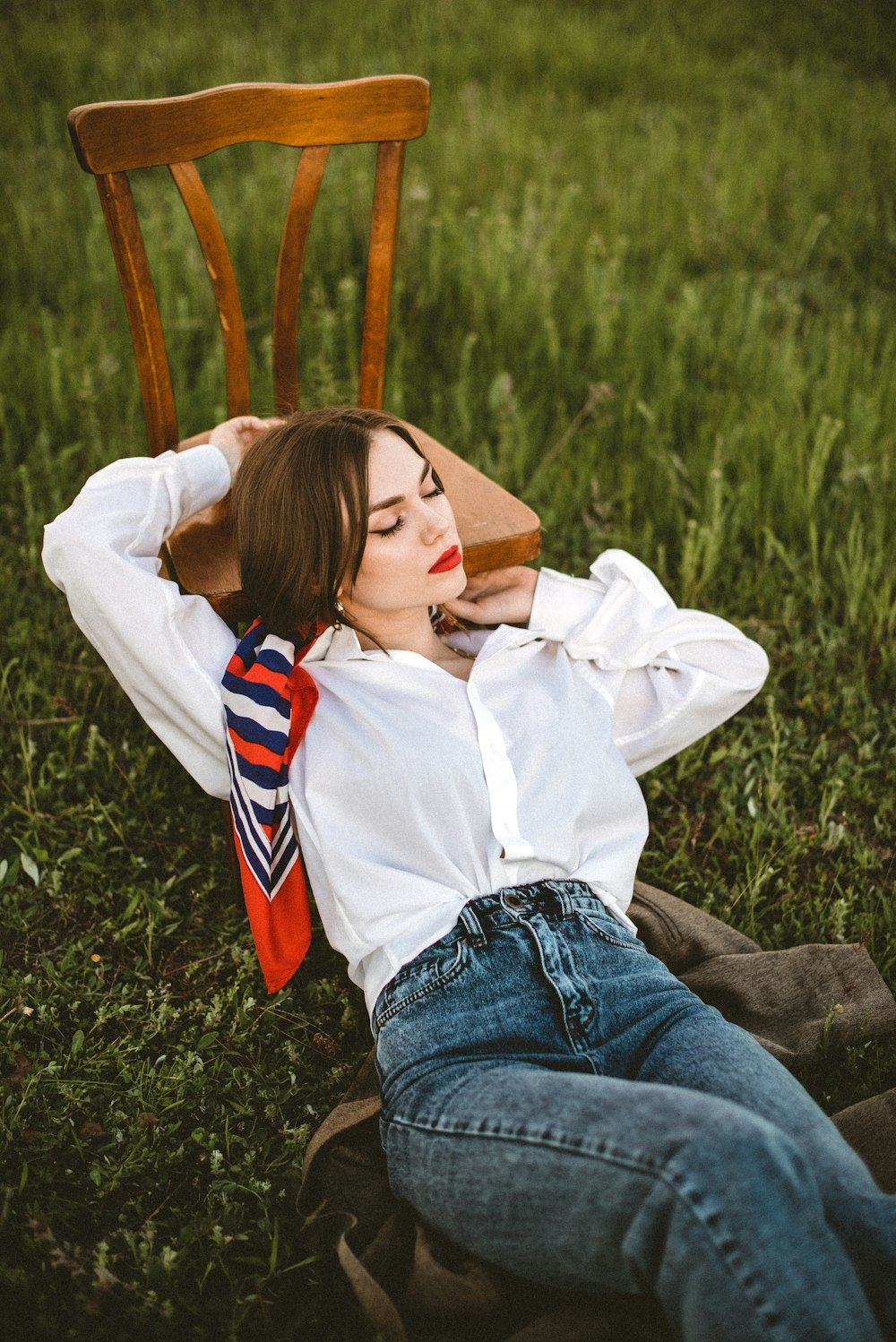 woman in white long sleeve shirt and blue denim jeans lying on green grass field during