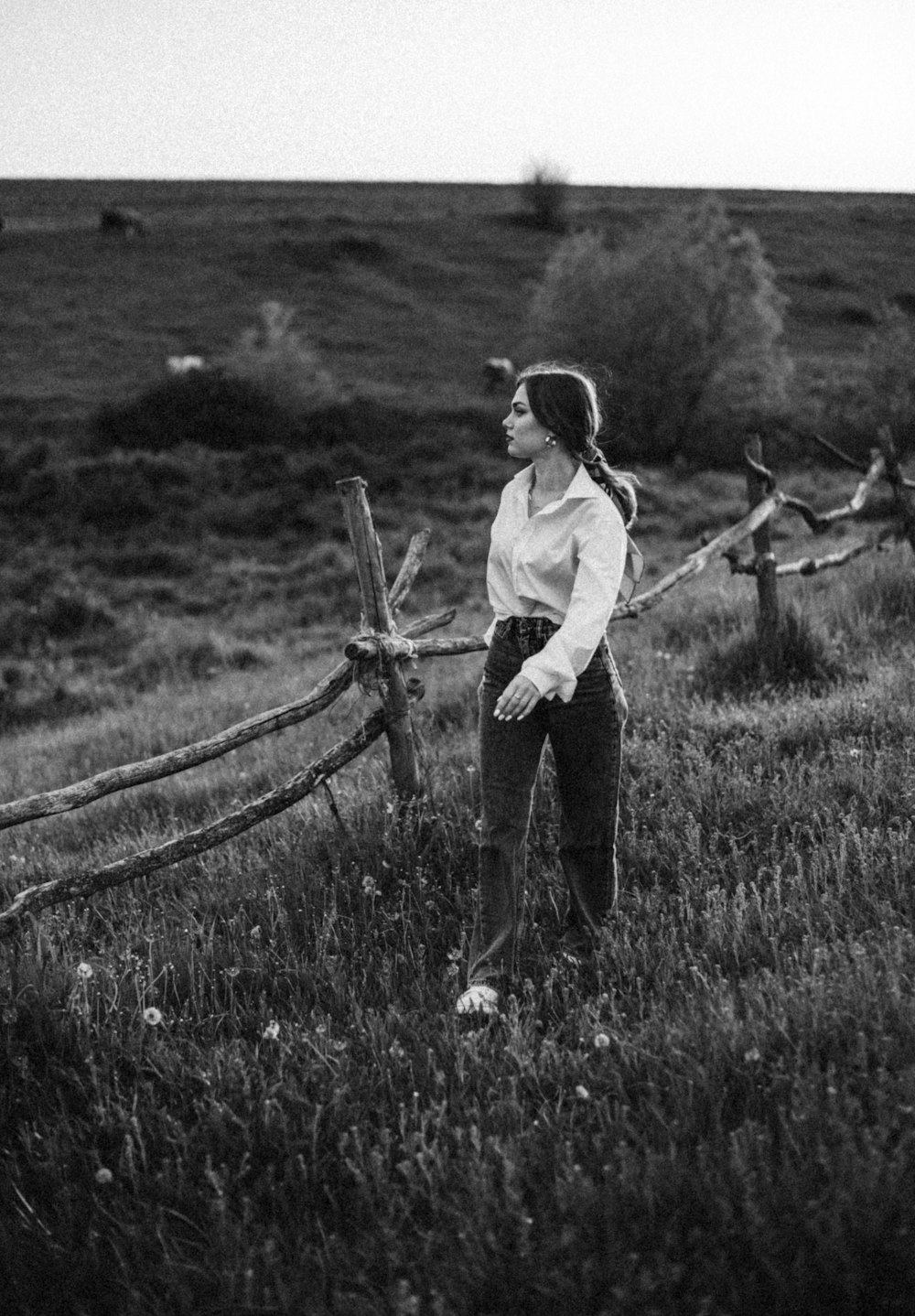 a woman standing in a field next to a fence