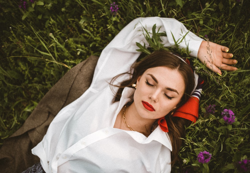 woman in white button up shirt lying on purple flower field during daytime