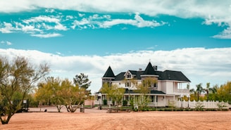 white and black house near green trees under blue sky during daytime