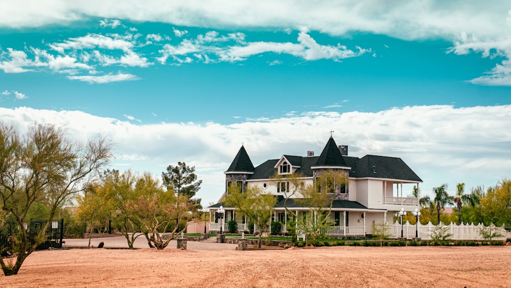 white and black house near green trees under blue sky during daytime