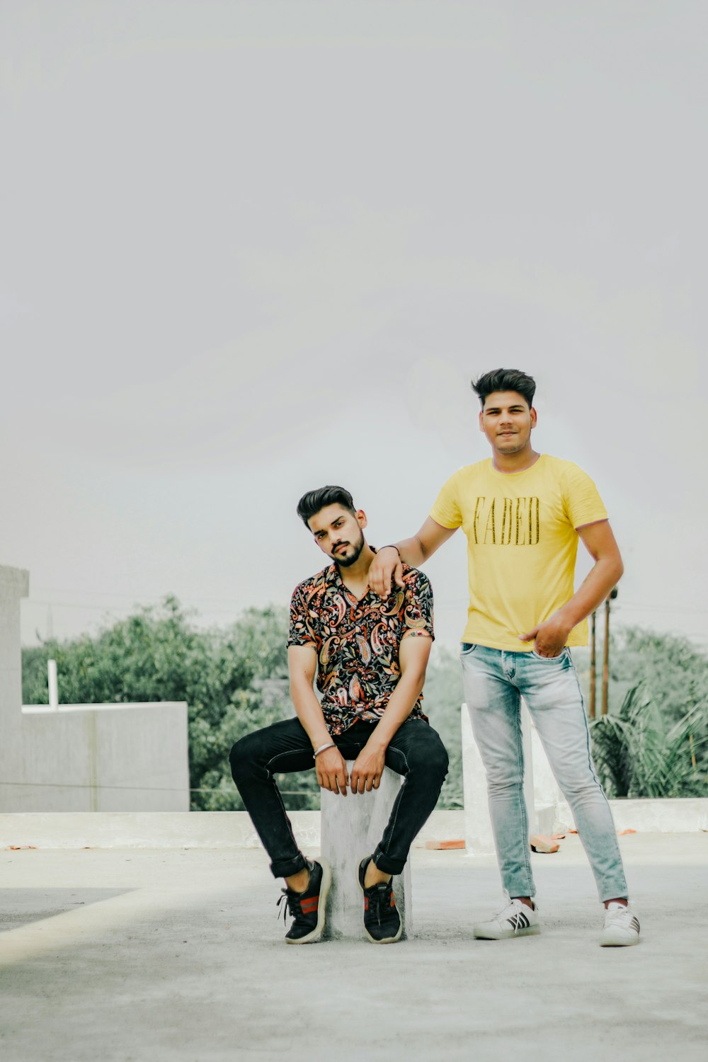 man in yellow crew neck t-shirt standing beside woman in black and white floral long