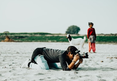 a man laying in the sand with a camera