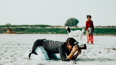 a man laying in the sand with a camera