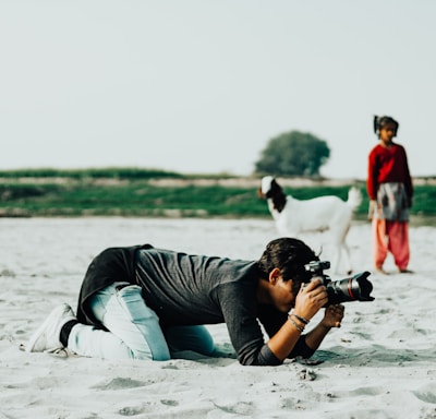 a man laying in the sand with a camera