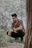 man in brown and white button up shirt and black pants sitting on brown tree log