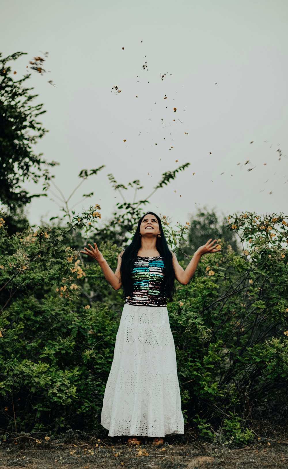 woman in black and white sleeveless dress standing near green plants during daytime