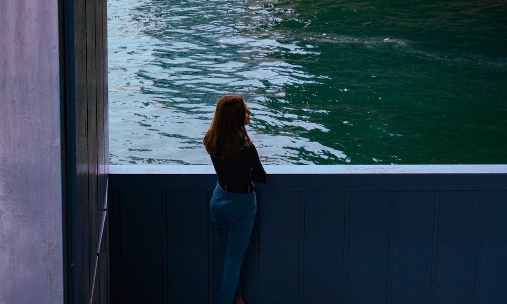 woman in black long sleeve shirt and blue denim jeans standing on dock