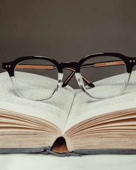 Close-up of a pair of modern eyeglasses resting on an open ophthalmology book.