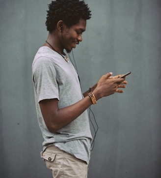 man in white crew neck t-shirt holding smartphone