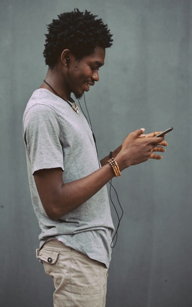 man in white crew neck t-shirt holding smartphone