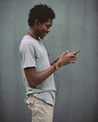man in white crew neck t-shirt holding smartphone