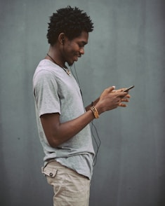 man in white crew neck t-shirt holding smartphone