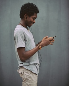 man in white crew neck t-shirt holding smartphone