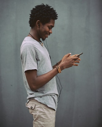 man in white crew neck t-shirt holding smartphone