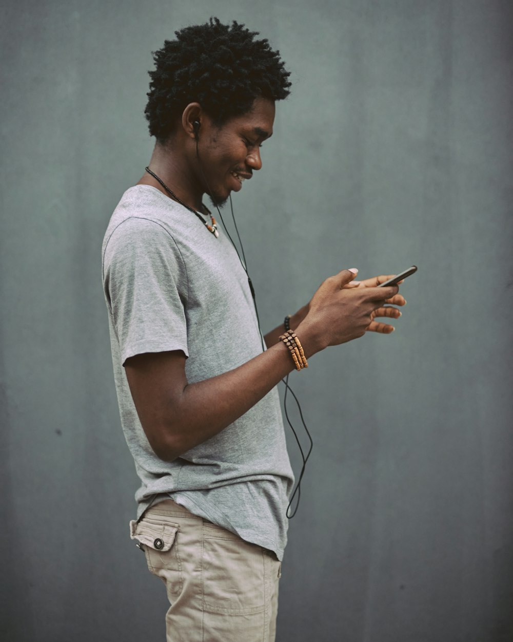 hombre con camiseta blanca de cuello redondo sosteniendo un teléfono inteligente