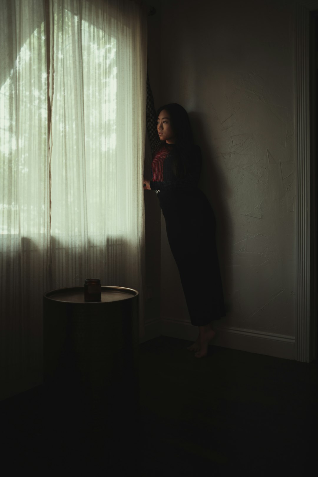 woman in black dress standing beside window