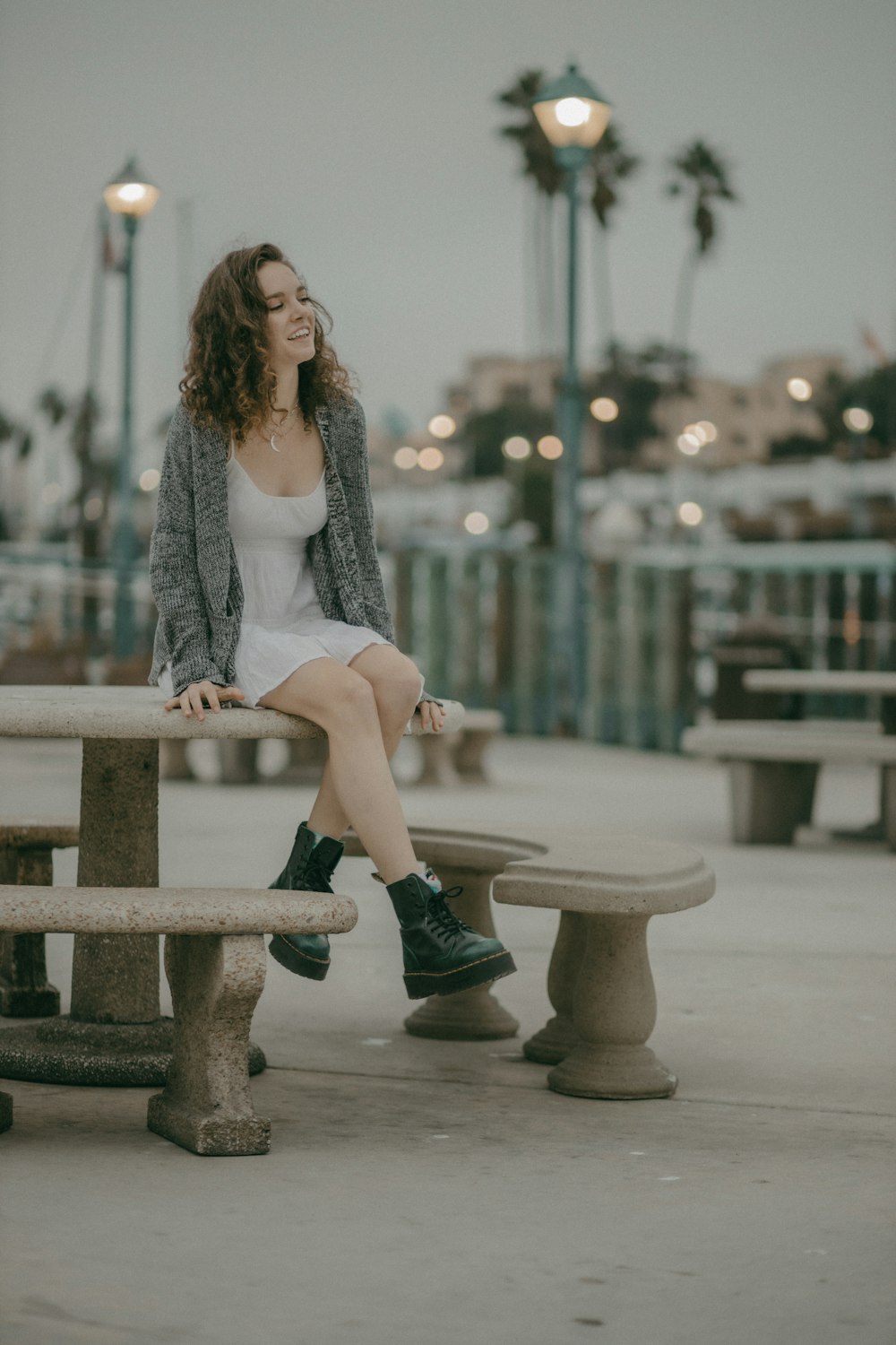 woman in gray cardigan sitting on brown concrete bench during daytime