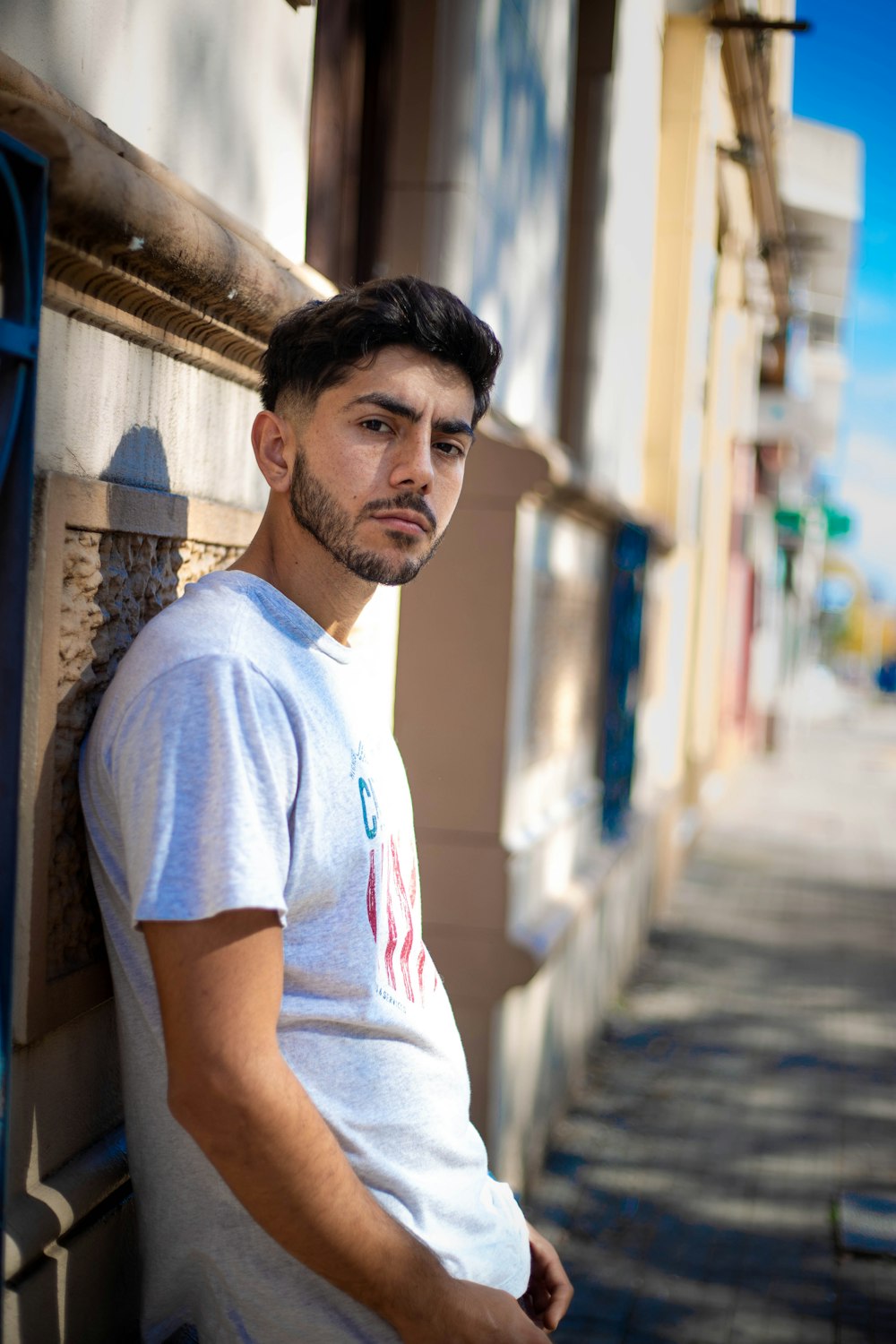 man in white crew neck t-shirt standing near building during daytime